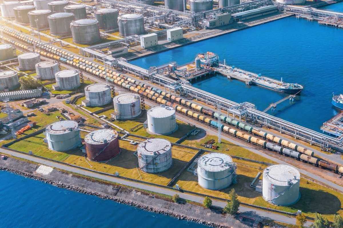 Import/export shipping terminal intersected by a rail line stacked with railroad tanker cars for liquid transport