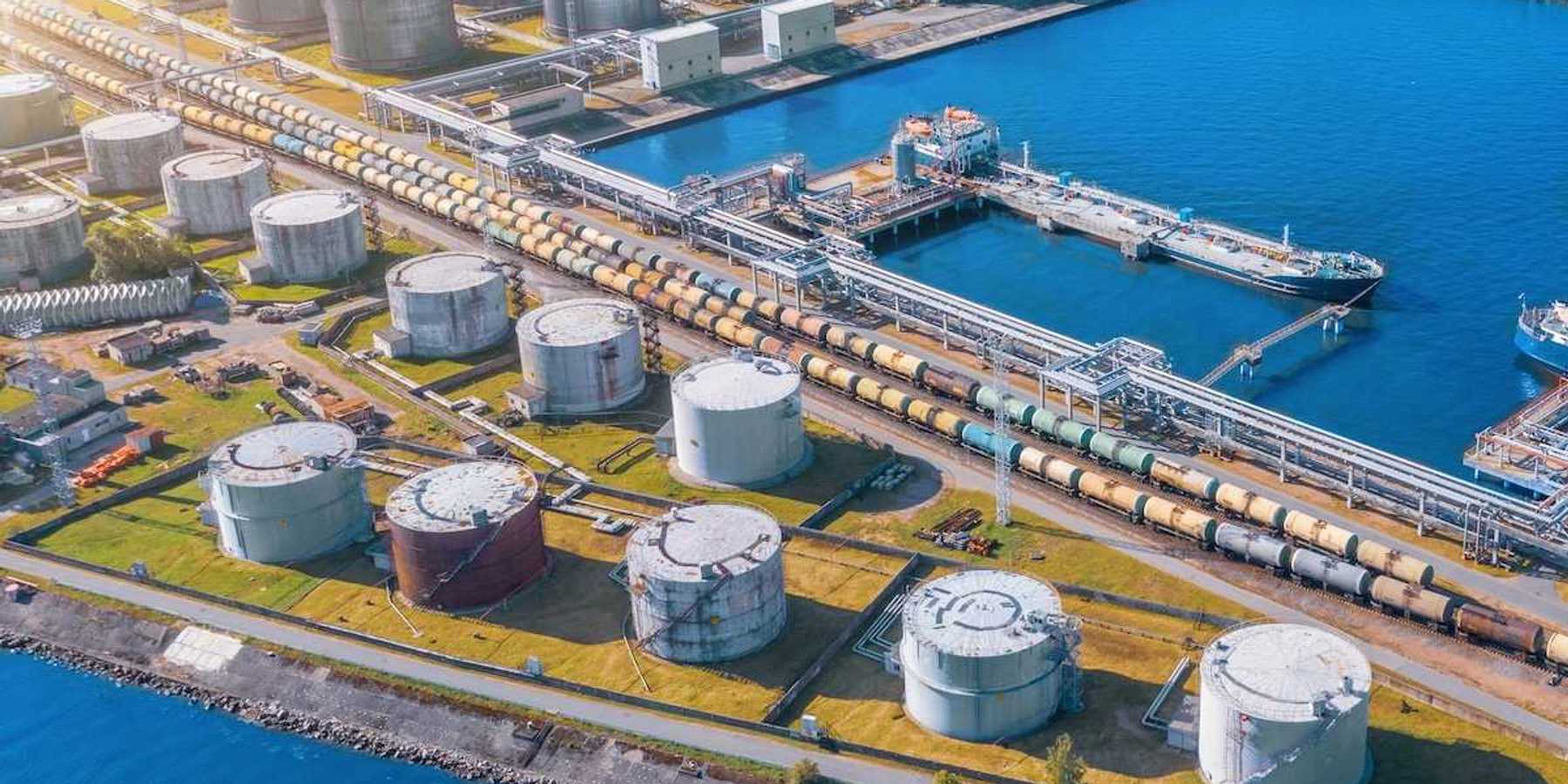 Import/export shipping terminal intersected by a rail line stacked with railroad tanker cars for liquid transport