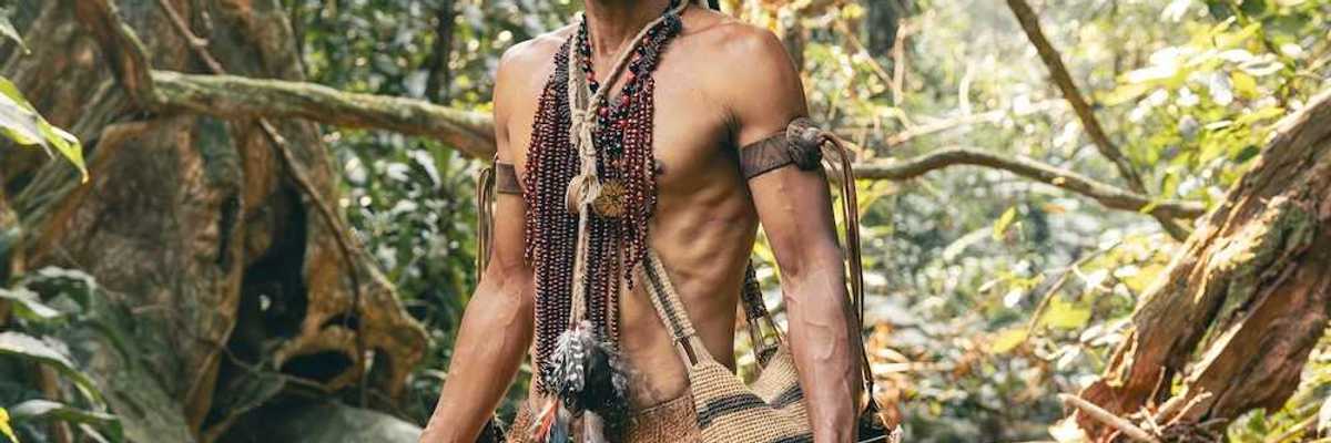 Indigenous Amazonian clad in traditional garb, standing in a rain forest
