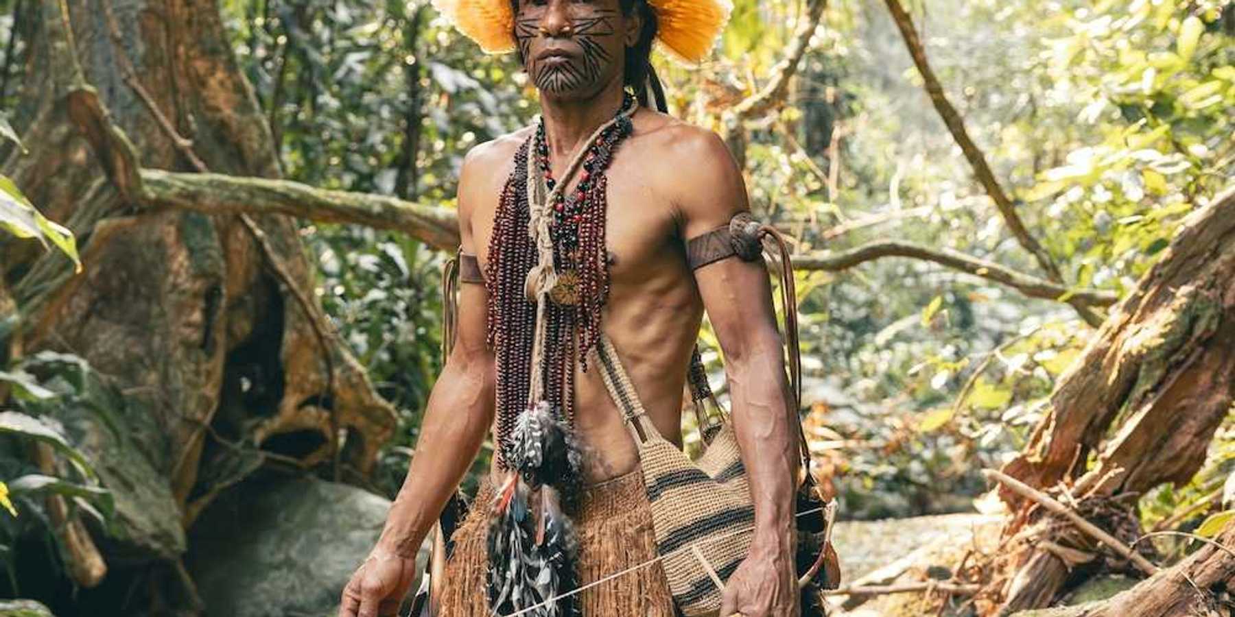 Indigenous Amazonian clad in traditional garb, standing in a rain forest