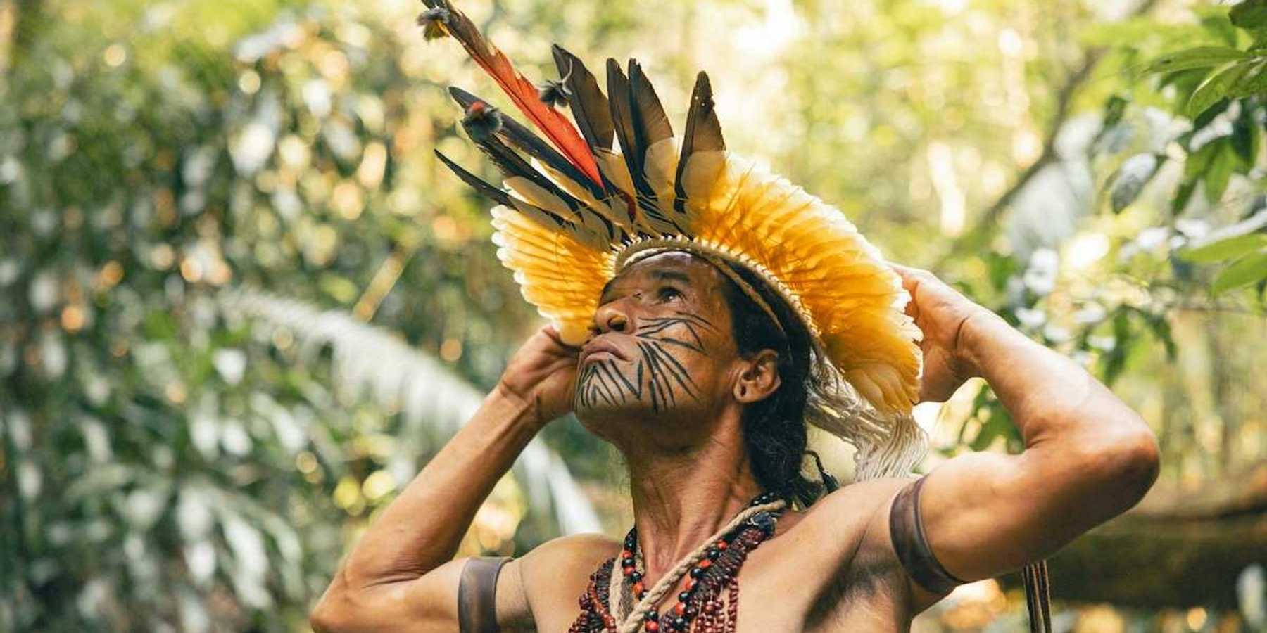 Indigenous Amazonian in traditional dress seemingly contemplative