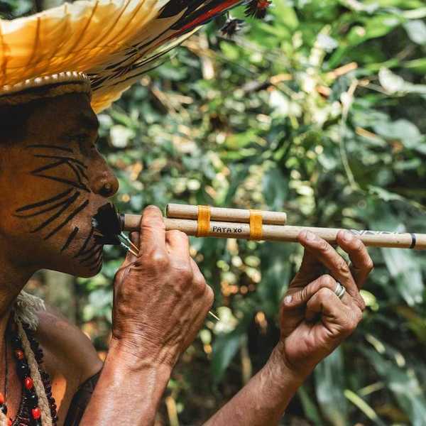 Indigenous Amazonian person using a blow-dart gun