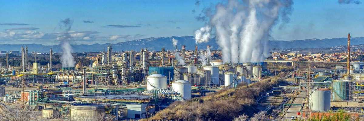 Industrial complex with polluting smoke rising from stacks.