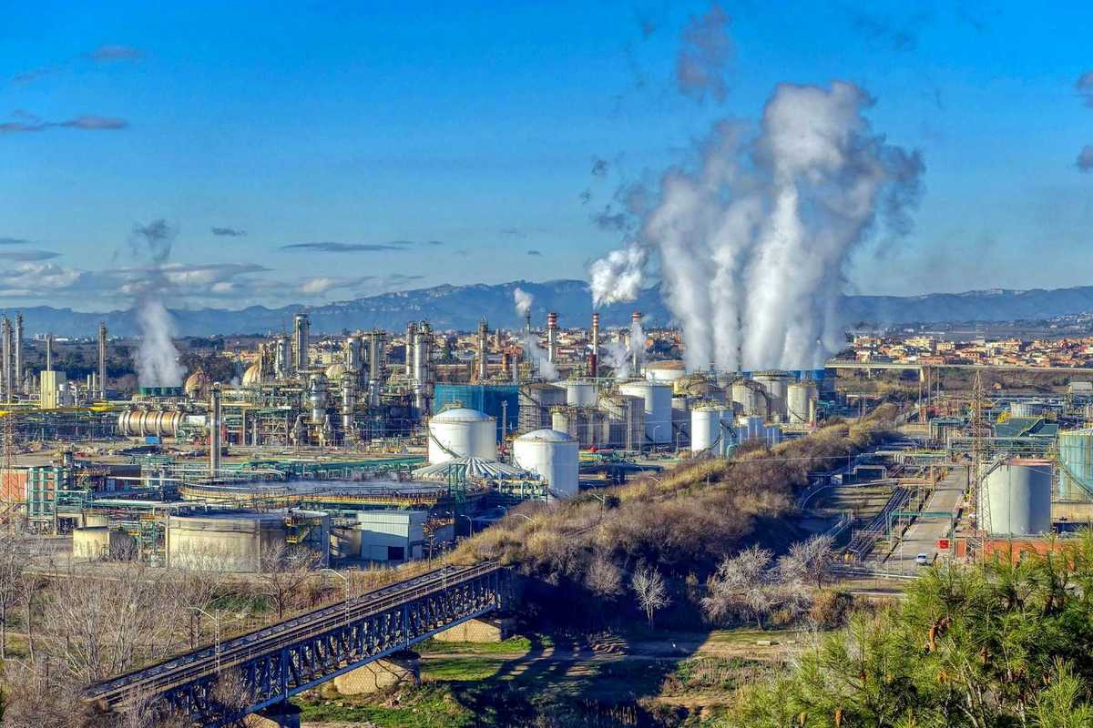 Industrial complex with polluting smoke rising from stacks.