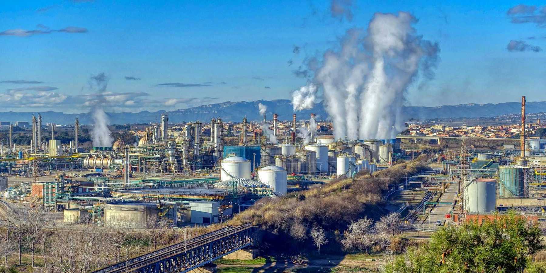 Industrial complex with polluting smoke rising from stacks.