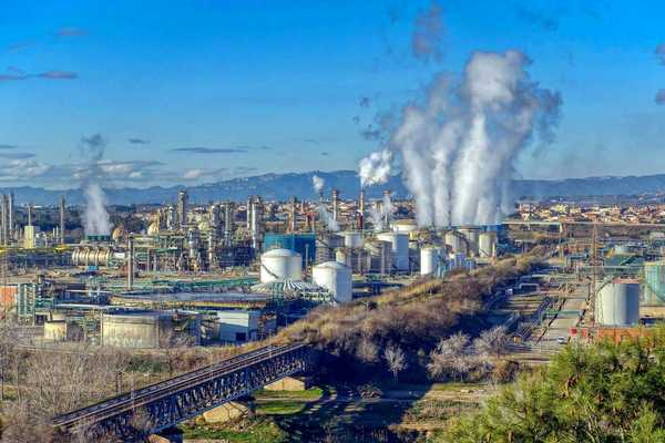 Industrial complex with polluting smoke rising from stacks.