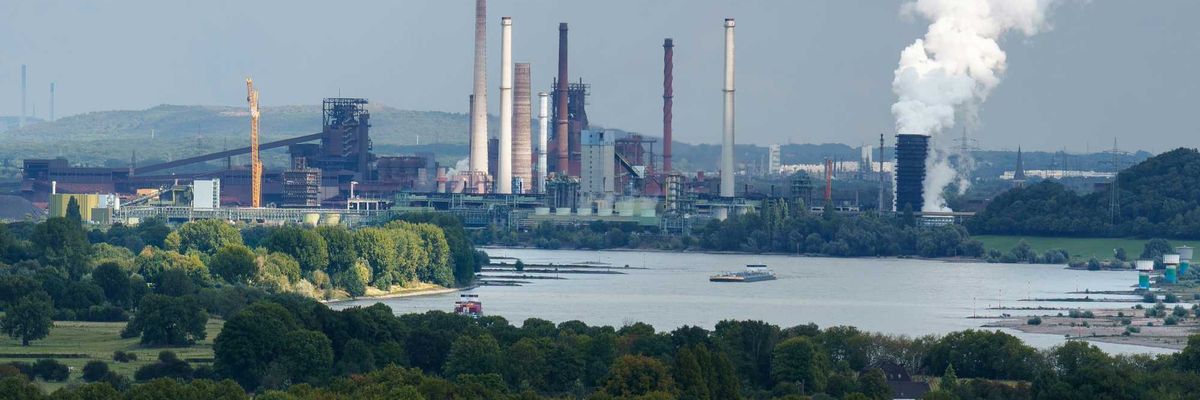Industrial complex with smokestacks near a body of water.