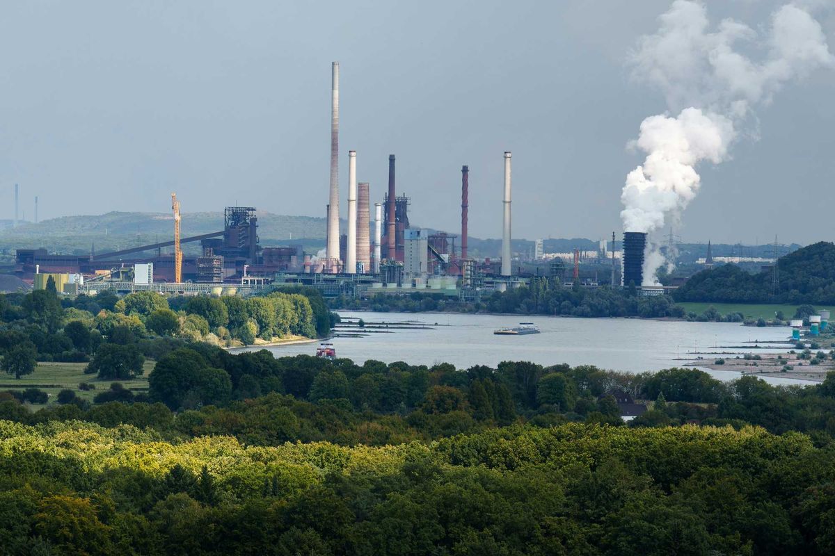 Industrial complex with smokestacks near a body of water.