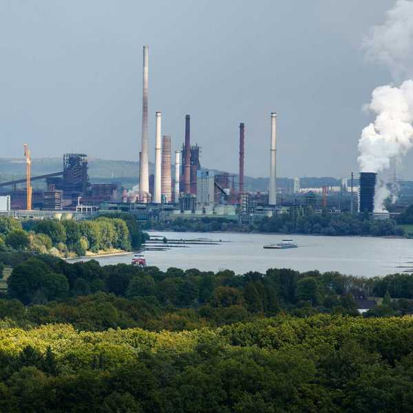 Industrial complex with smokestacks near a body of water.