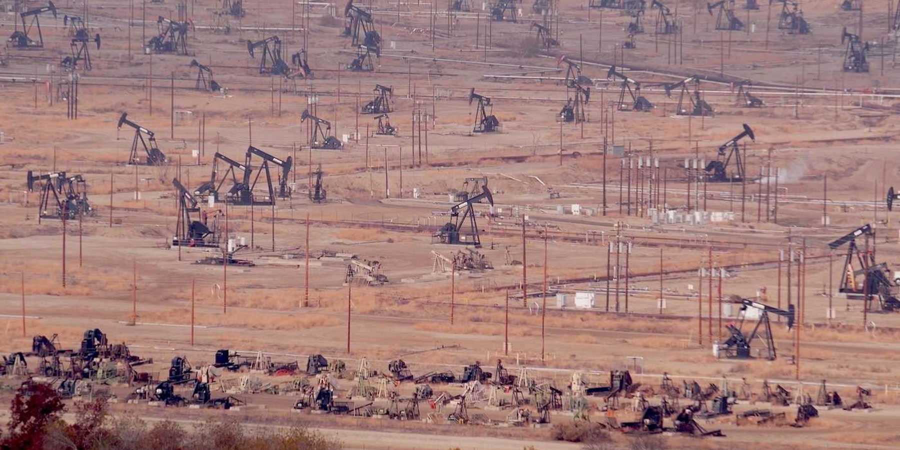 Industrial landscape, oil derricks in desert valley.