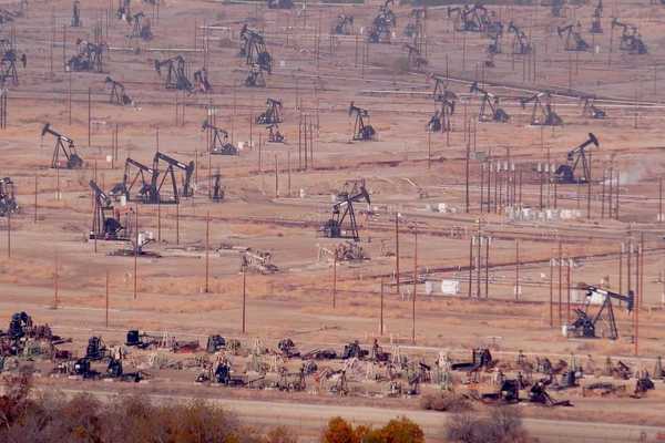 Industrial landscape, oil derricks in desert valley.