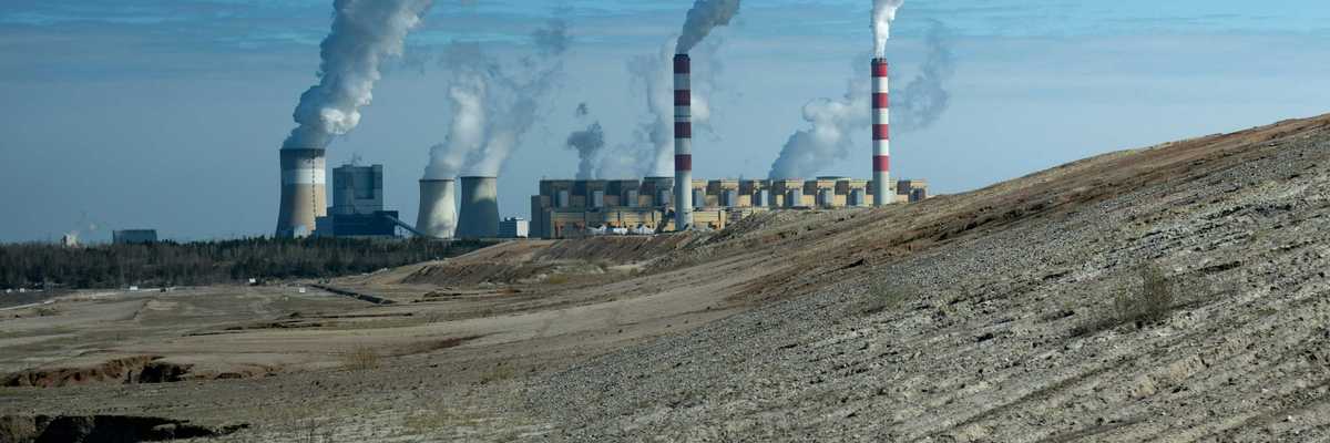 Industrial power plant with smoke stacks under blue sky.