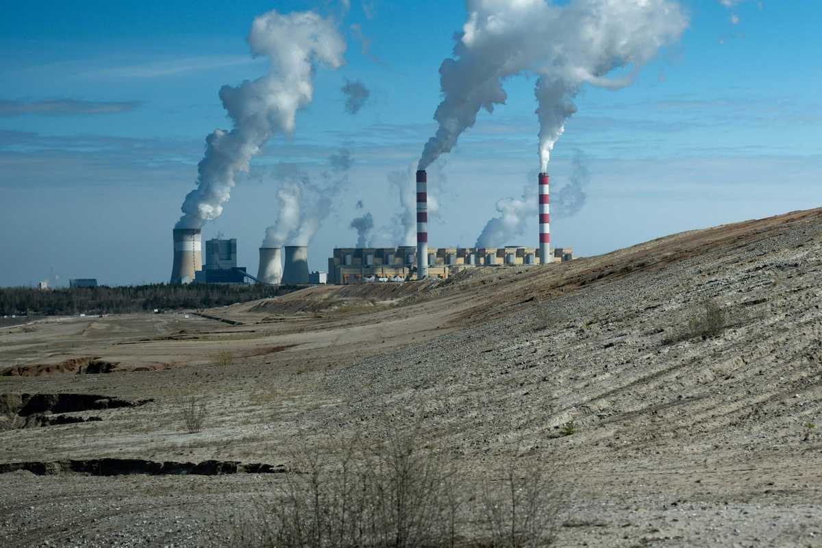 Industrial power plant with smoke stacks under blue sky.
