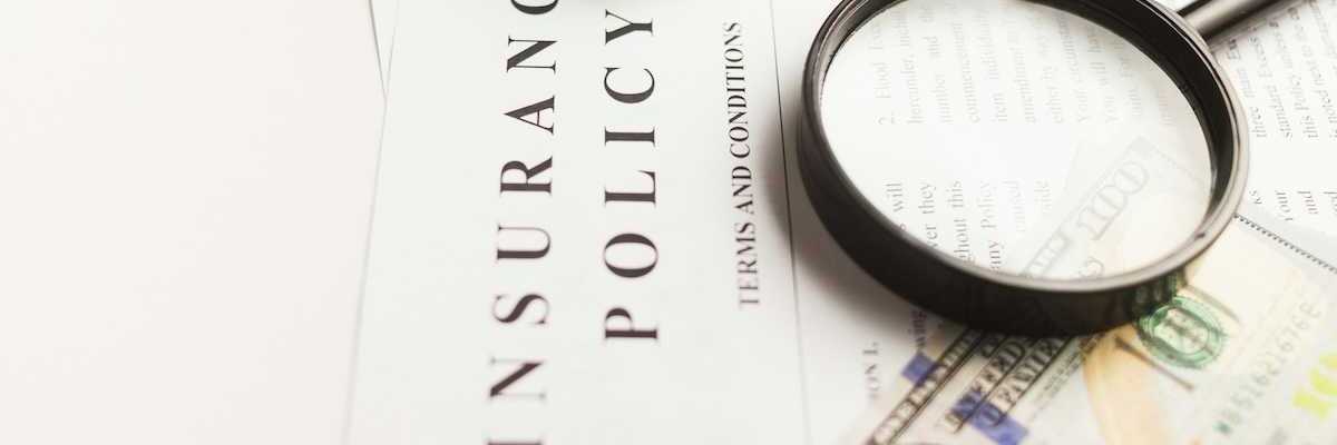 Insurance policy with magnifying glass, miniature auto, and hundred-dollar bill
