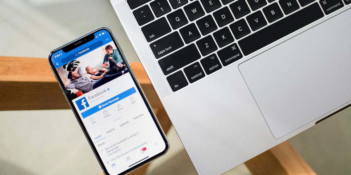 iPhone with Facebook on the screen beside a MacBook