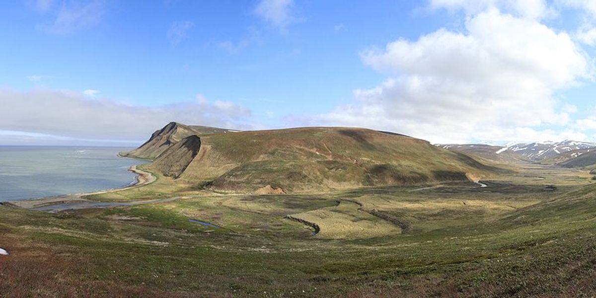 Island with low green hills with water in the distance.