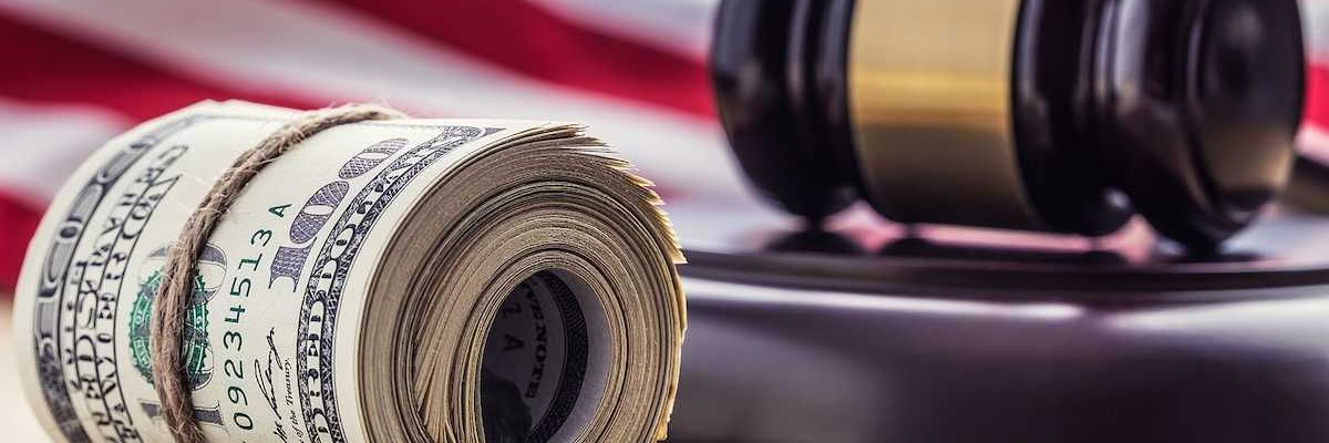 Judge's hammer gavel and rolled banknotes with USA flag in the background.