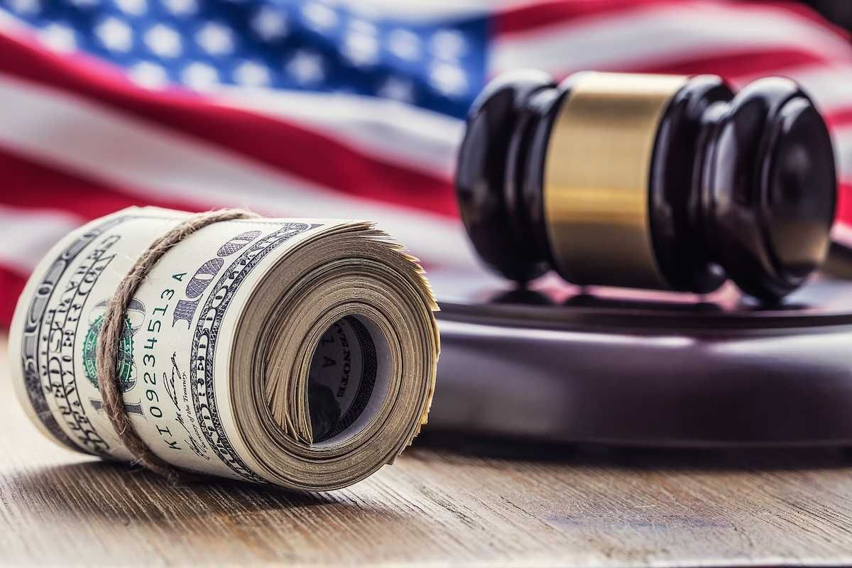 Judge's hammer gavel and rolled banknotes with USA flag in the background.
