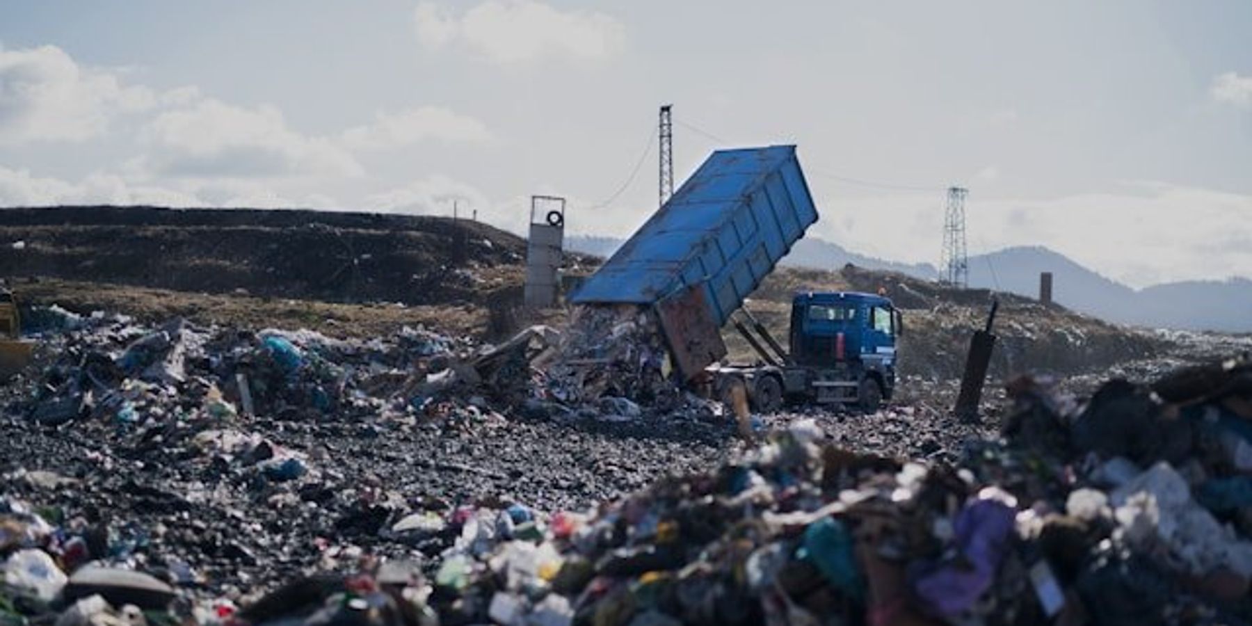 Landfill with truck dropping off a load of trash.