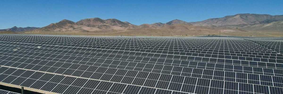 Large expanse of solar panels stretching out to distant hills.