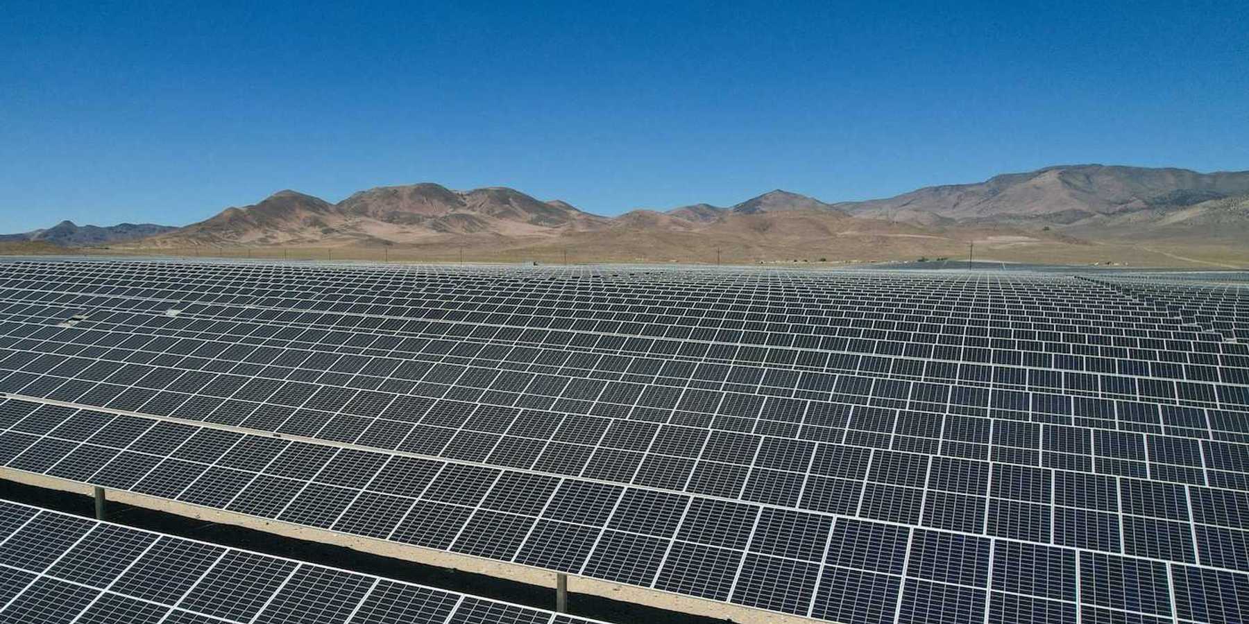 Large expanse of solar panels stretching out to distant hills.