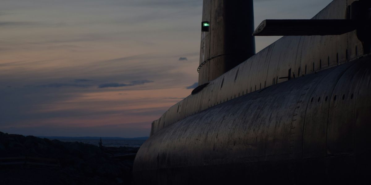 Large submarine in a shipyard at dusk.