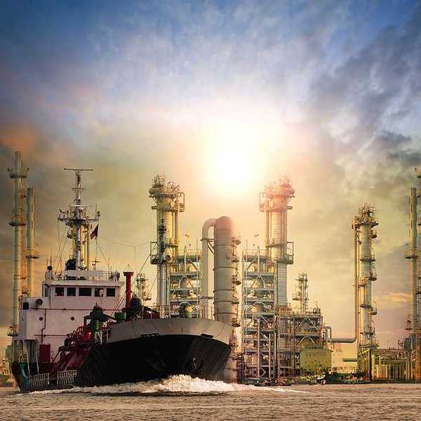 LNG tanker ship with oil and gas refinery plant in background