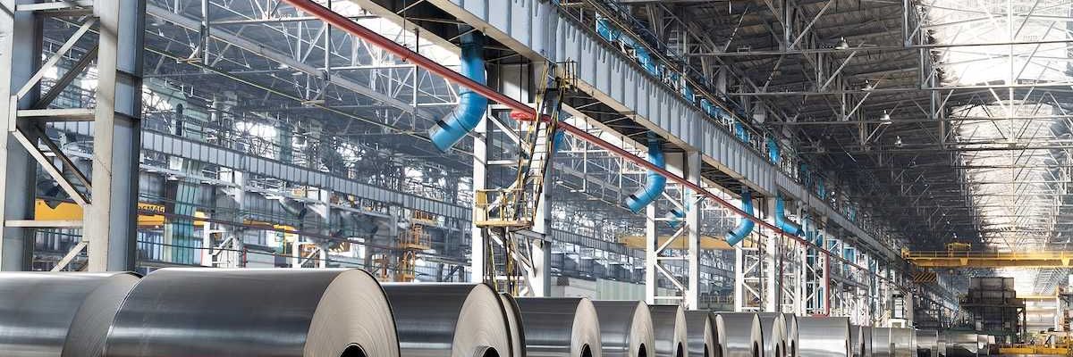 Long row of rolls of aluminum in production shop of plant.