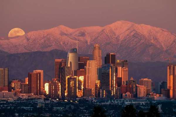 Los Angeles skyline with snowcapped San Gabriel mountains in background and full moon rising