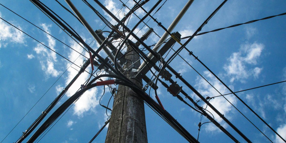 Low angle photo of electric post with cables.