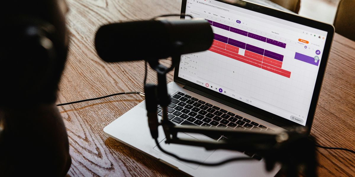 Macbook on a wooden table with a microphone.