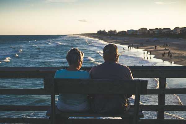 man and woman sitting on bench at beach