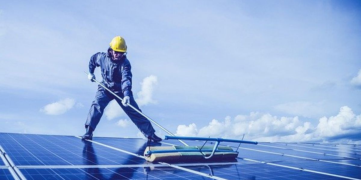 Man cleaning solar panels on a roof.