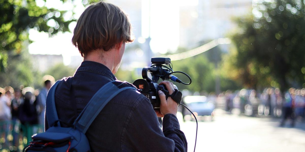 man in black jacket holding black dslr camera