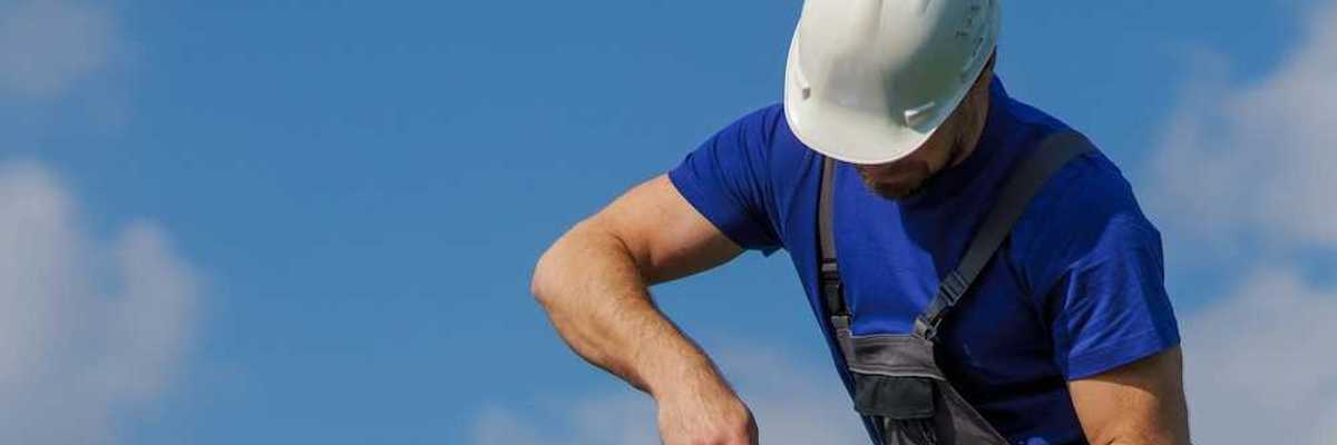 Man in white hard hat and blue shirt installing solar panels