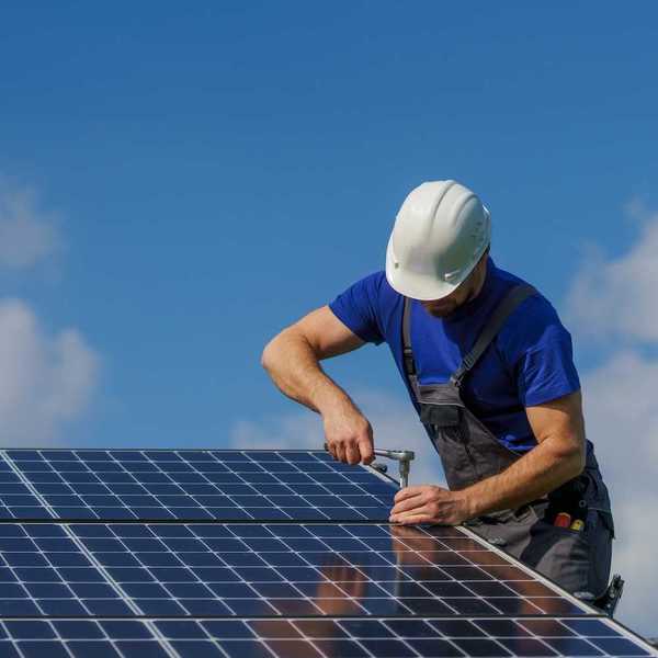 Man in white hard hat and blue shirt installing solar panels