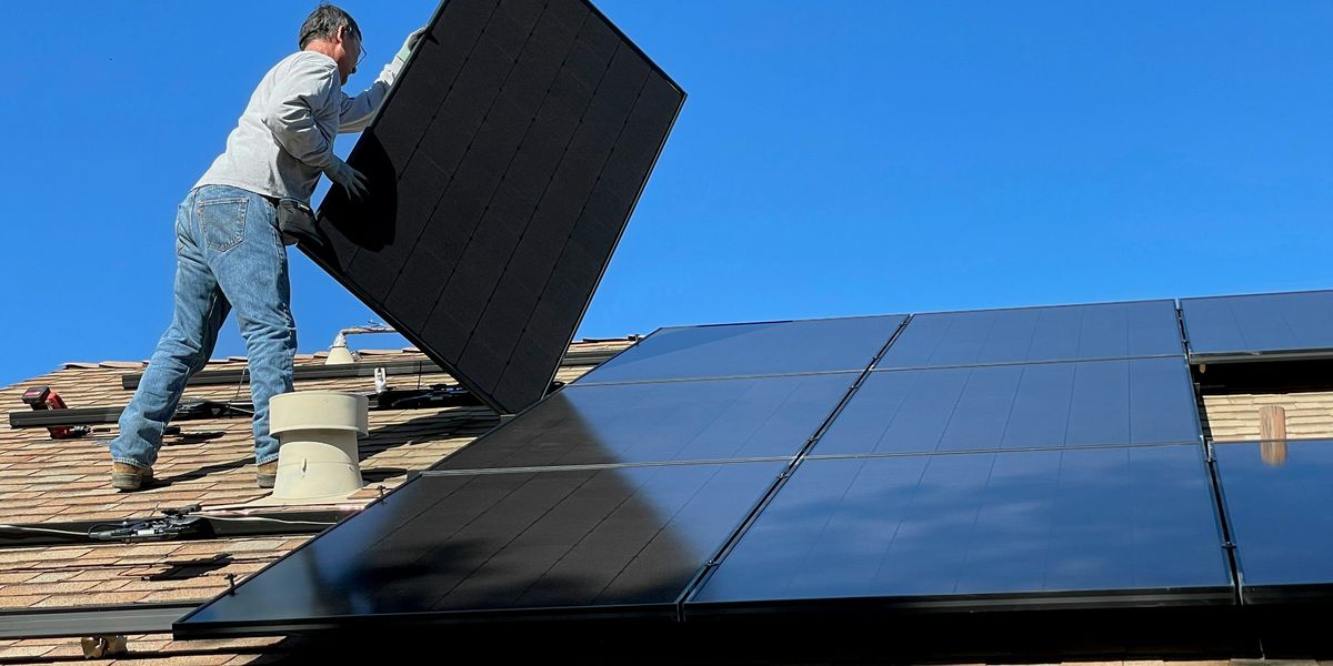 man in white shirt and blue denim jeans a solar panel on a roof