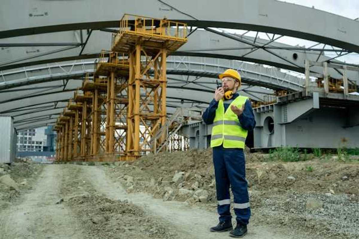 Man in yellow safety vest standing under a building roof being built