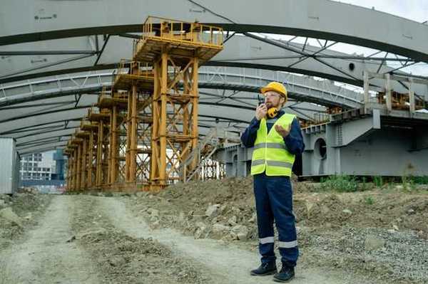 Man in yellow safety vest standing under a building roof being built