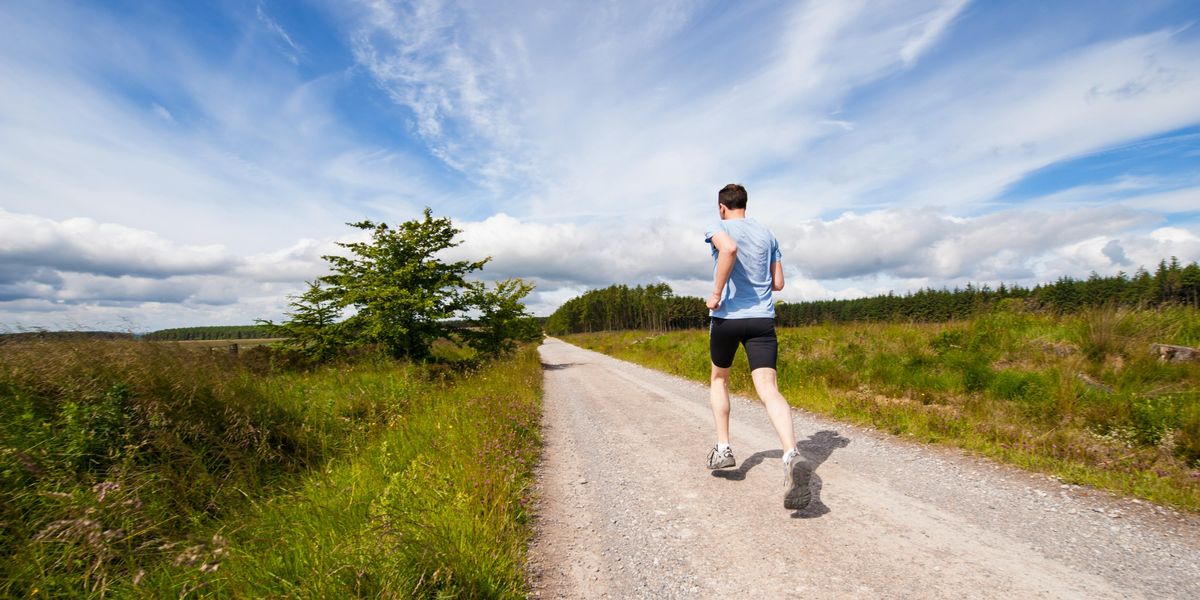 man running on road near grass field