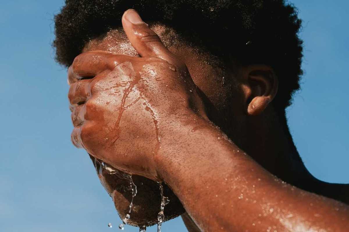 Man splashing water on face for heat relief