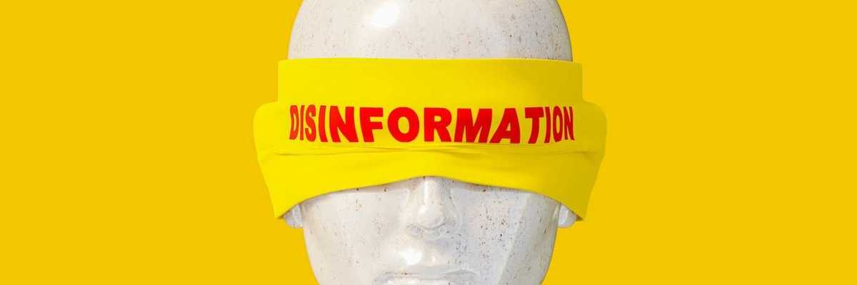Mannequin head shot wearing a yellow blindfold labeled "disinformation" in red letters.