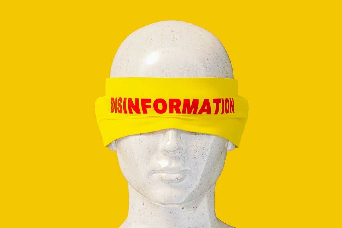 Mannequin headshot wearing a yellow blindfold labeled "disinformation" in red letters