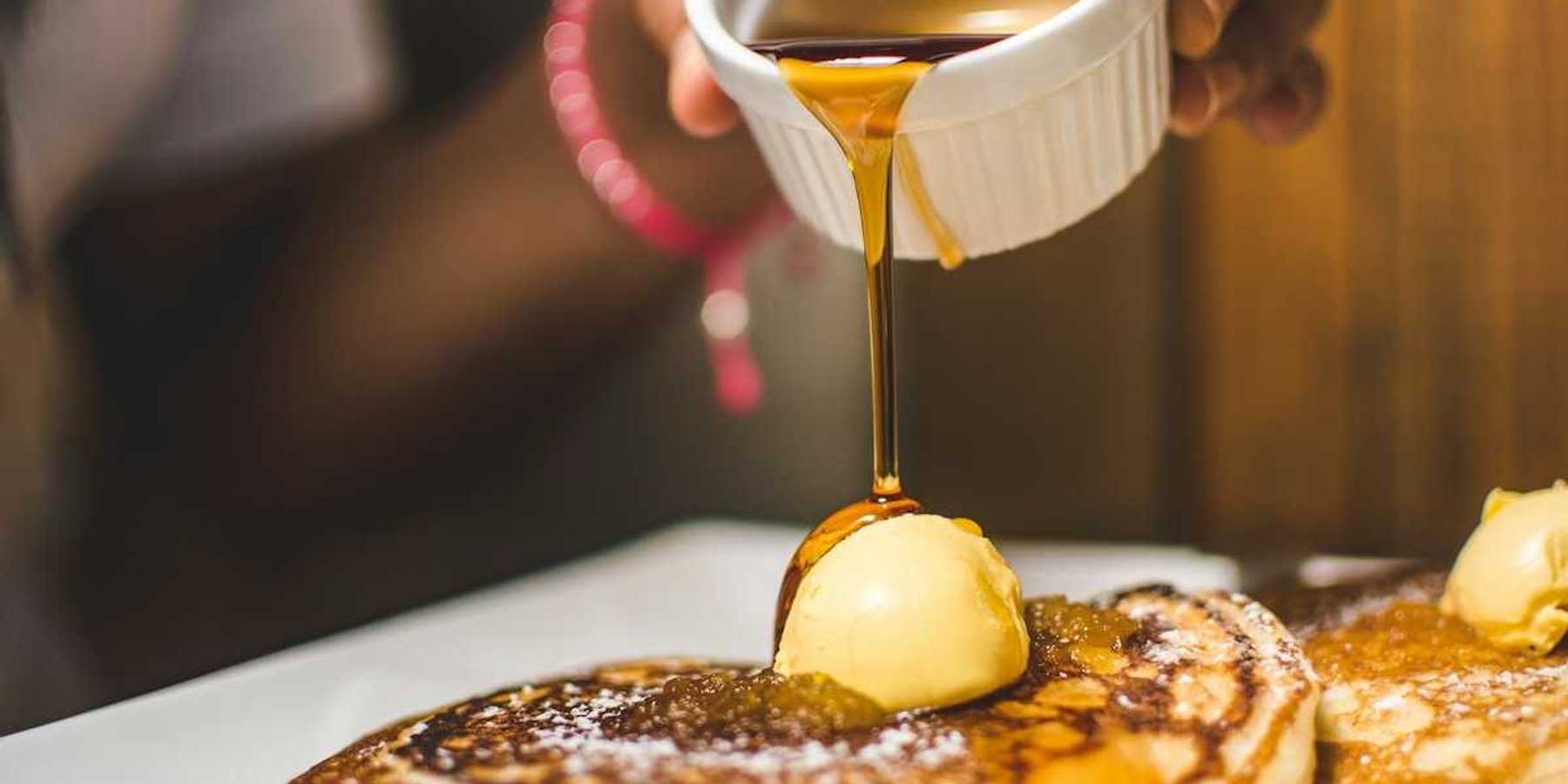 Maple syrup being poured over pancakes