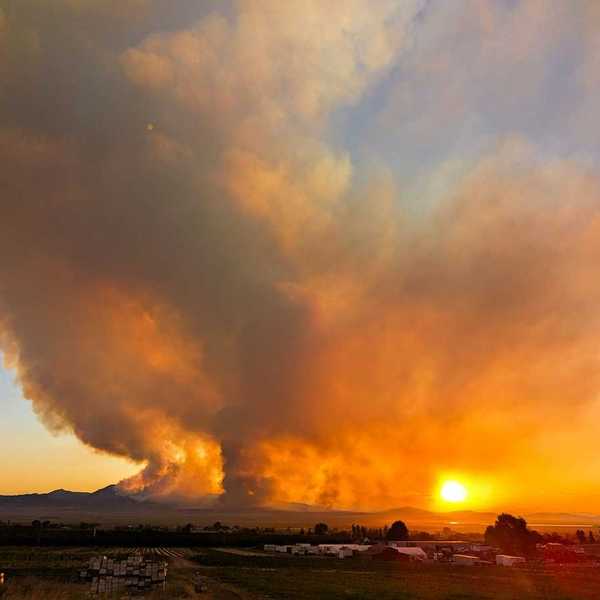 Massive wildfire partially obscuring a setting (or rising sun)