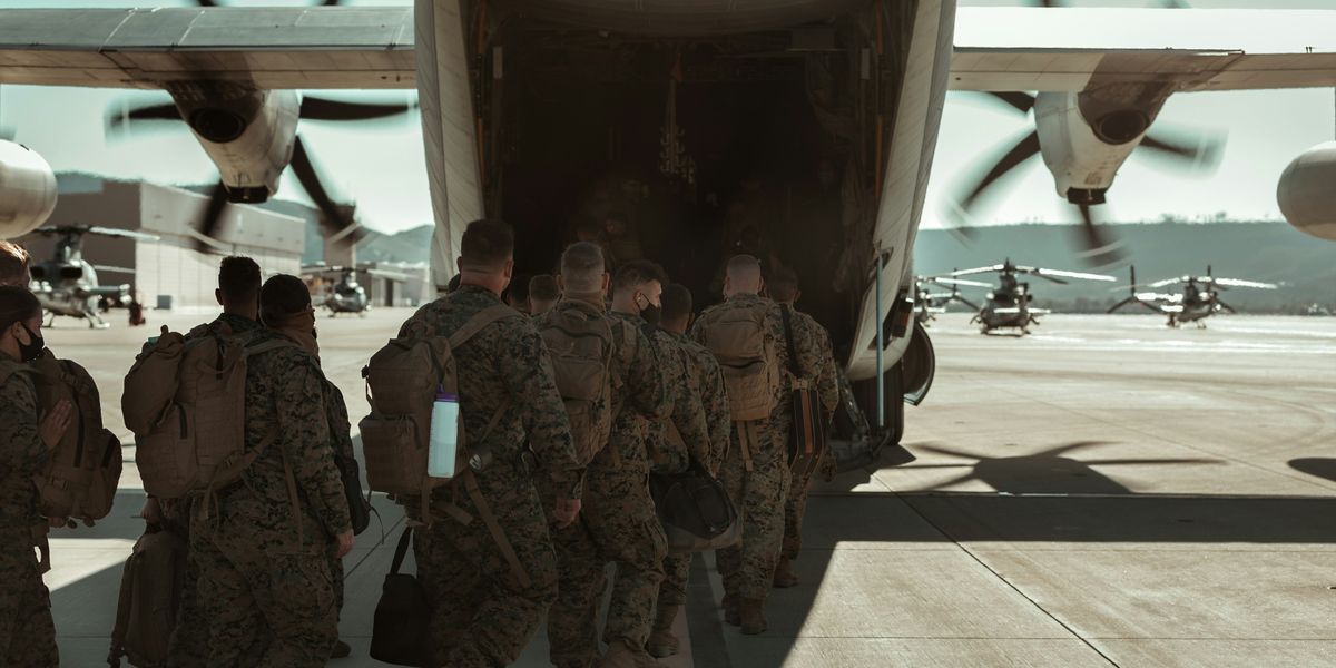 Military members in fatigues walking onto an airplane