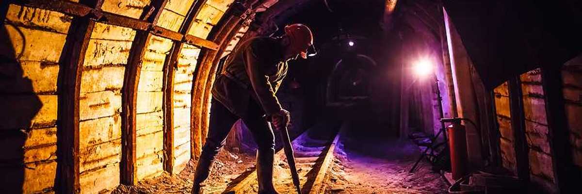 Miner working a jackhammer in a coal mine.