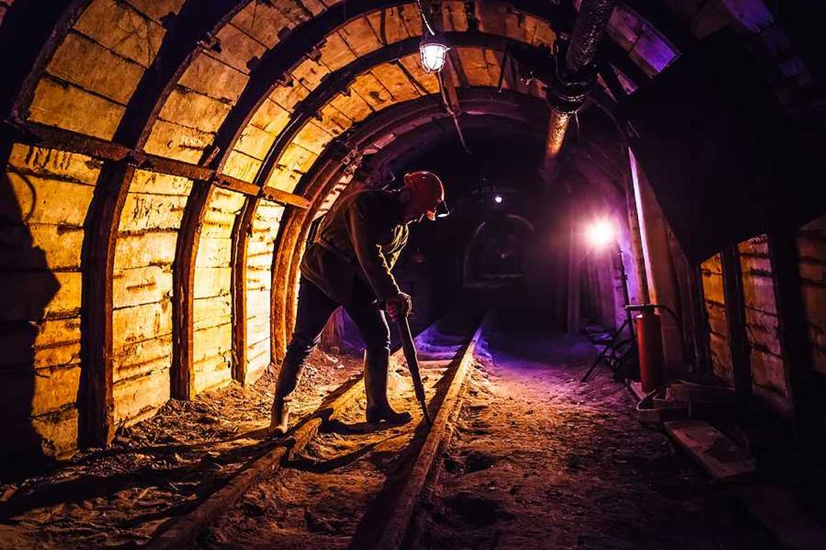 Miner working a jackhammer in a coal mine.