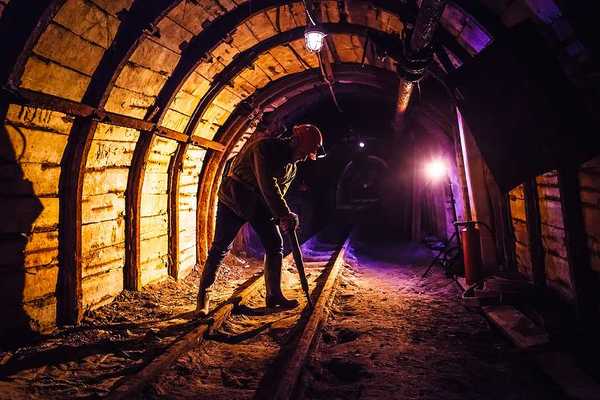 Miner working a jackhammer in a coal mine.