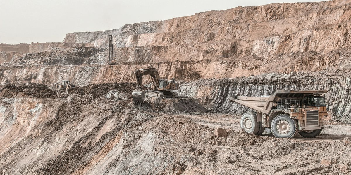 Mining pit with equipment and a truck in the foreground.